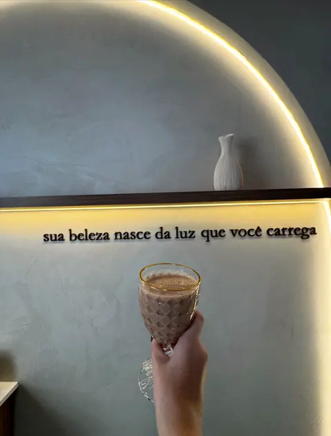 Taça de café em frente à frase “sua beleza nasce da luz que você carrega”, no arco iluminado da clínica