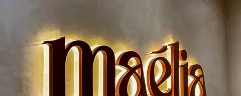 Letreiro iluminado da Maélia na parede da recepção